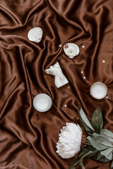 Woman candle. Aroma candle in the shape of a female body on elegant silky background. Minimalistic background