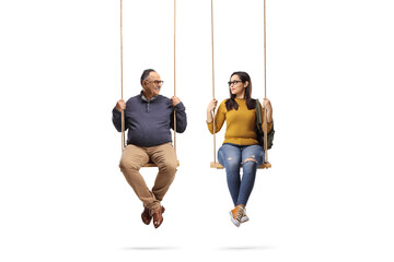 Father and daughter sitting on wooden swings and looking at eachother