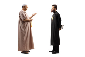 Full length profile shot of a muslim man in traditional clothes talking to a christian priest