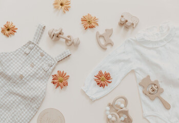 Light soft baby pants with wooden toys and flowers. Fashion newborn, bohemian style, neutral beige colors. Flat lay, top view.