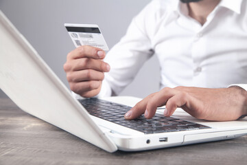 Businessman using laptop computer and holding credit card.