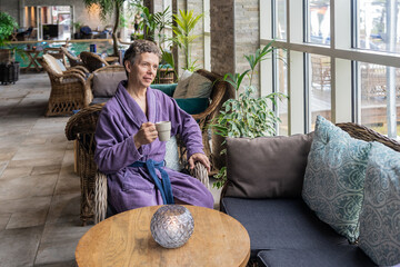 Middle aged man is resting in SPA hotel, relaxing and drinking coffee in the morning. Handsome attractive male brunet in bathrobe enjoying his morning coffee at luxury SPA hotel by the pool. Lifestyle