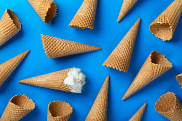 Ice cream and waffle empty ice cream cones on blue background, flat lay