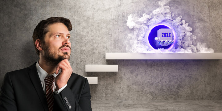 thinking businessman in front of a wall with a robot hand delivering a cube with the German message for GOALS out of a portal as a concept for algorithms in business decisions