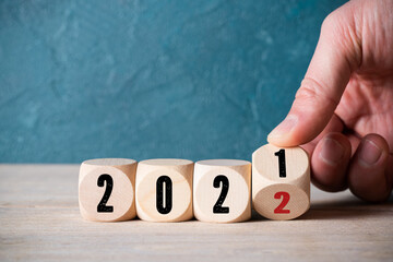 hand turning a cube from 2021 to 2022 on wooden background