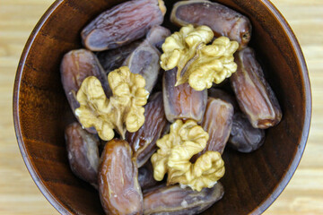 Wooden bowl with dates and walnut kernels. Fruit on a wooden tray. Fruit dates. Walnut kernels.