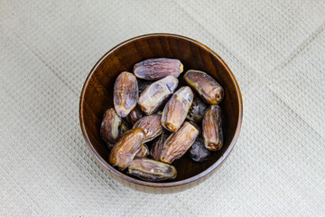 Wooden bowl with dates on the table. Fruit on a wooden tray. Fruit dates. Walnut kernels. The concept of Ramadan.
