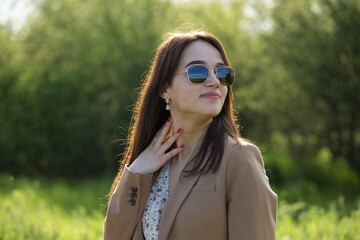 Portrait of a positive cheerful brunette girl in a green spring park.