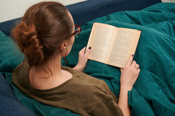 photo from the back of a girl reading a book learning at home, a hobby