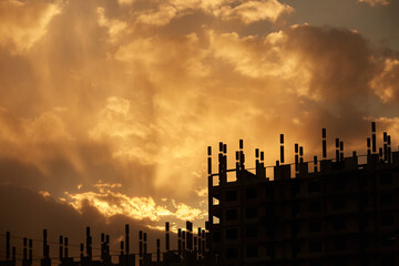 Fototapeta na wymiar The silhouette of a building under construction. Sunset silhouettes of high-rise buildings under construction against the sky with clouds and the setting sun