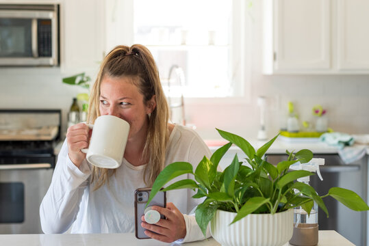 Smiling young woman drinking coffee and using mobile phone