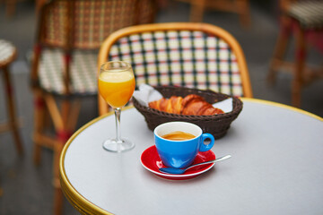 Cup of fresh hot coffee, orange juice and traditional French croissant on table of Parisian outdoor cafe in Paris