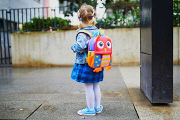 Adorable toddler girl with funny backpack ready to go to daycare, kindergarten or school