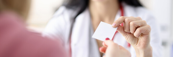 Obraz premium Doctor hands over business card to patient in office