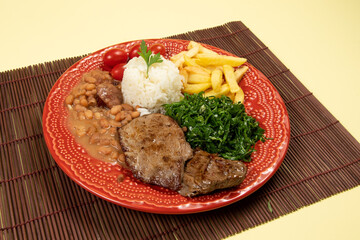 typical Brazilian basic dish with rice, beans, steak, french fries, braised cabbage and tomato