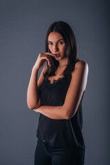 Sensual studio portrait of a sexy woman standing with one arm crossed on a gray background