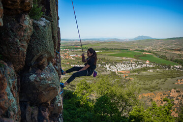 Young lady climbing on the rock in mountains