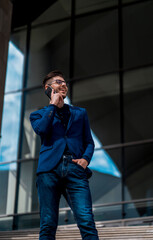 Portrait of cheerful young man looking sideways while talking on smartphone outdoors