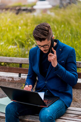 Young manager talking on mobile and work on his lap top at city center