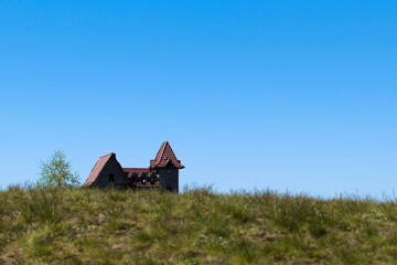 Fototapeta na wymiar House with tiled roof and turrets against blue sky. Blurred foreground with green grass