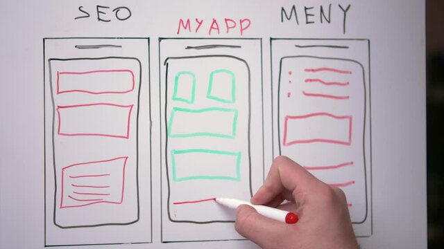 The hand of a young white guy is writing on a white magnetic board the concept of application development, the concept of teaching work and learning at a distance