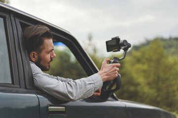 Side view of influencer man films a travel video using smartphone with steadycam