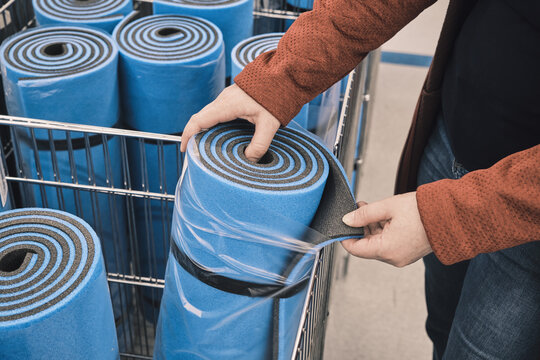 Woman in a shop chooses a blue travel, sports mat to buy. The concept of an active lifestyle and travels with a tent. Hands close up shot