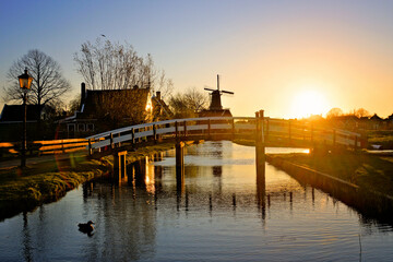 Dutch countryside sunset with windmill and bridge along a canal at the historic village of Zaanse Schans, Netherlands