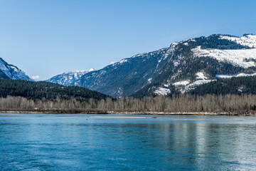 early spring Columbia river with snow on mountains blue sky British Columbia Canada