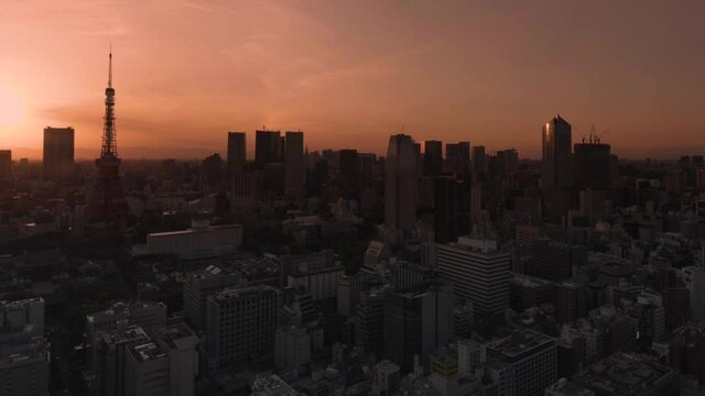 tokyo, japan - may 10 2021: Pan video of a cityscape of the Daimon district of Tokyo city with a sunset sky behind the Tokyo tower and Roppongi Hills skyscrapers.