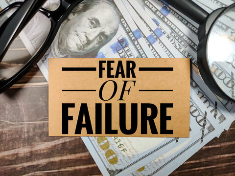 Business concept.Text FEAR OF FAILURE with magnifying glass,glasses and banknote on brown wooden background.