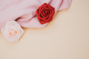 Pair of beautiful roses on a wrinkled pink piece of cloth with copy space below on pastel background