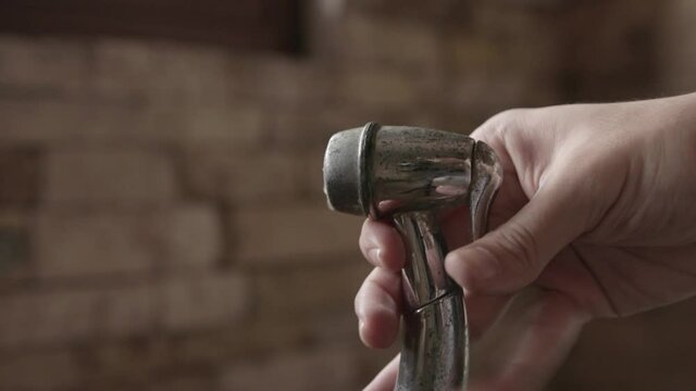 Close-up on Male Hand Holding Bidet Sprayer Head and Intermittent Pushing on it, 4K
