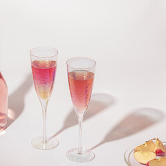 Bottle of rose wine and two crystal glasses on light background with hard sunlight at summer sunny day