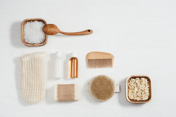 Fototapeta na wymiar Flat lay composition with bath accessories with small bottles with gel and shampoo, soap, sea salt, washcloth on table with copy space.