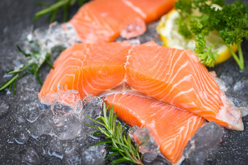 Raw salmon filet with herbs and spices on dark black background, Fresh salmon fish on ice