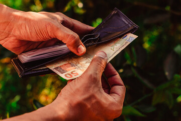 Hands take fifty brl out of the wallet