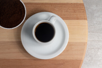 A cup of black coffee and ground coffee.