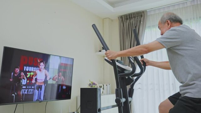 Asian old man doing exercise by learning online from video tutorial.