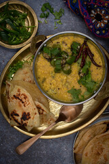 Indian vegan lentils and okra in traditional serving bowls, served with flat breads