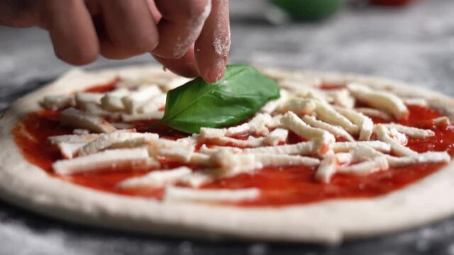 Close-up shot of chef hand preparing and cooking a fresh Napolitan Italian pizza dough for a traditional pizzaria restaurant in Italy. Napolitan food in a professional kitchen. Cinematic slow motion.