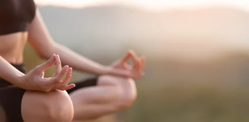 Foto op Canvas Close up with selective focus of hands woman sitting in yoga lotus pose outdoor at sunrise, meditating for balance. Horizontal banner view for website header design with copy space for text.  © Svetlana