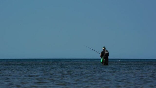 Fisherman fishing on the shallow sea water of the Mediterranean coastline