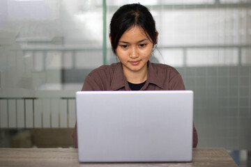 Attractive happy young girl student studying at the college library having video chat. 