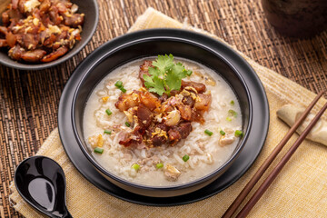 Minced pork congee, rice porridge, soup in Thai Chinese style topped with crispy fried garlic pork belly. This traditional, flavorful dish is a comfort food for many Thais often served as breakfast.