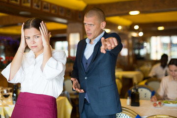 Angry man client of restaurant yelling at young waitress chasing her away
