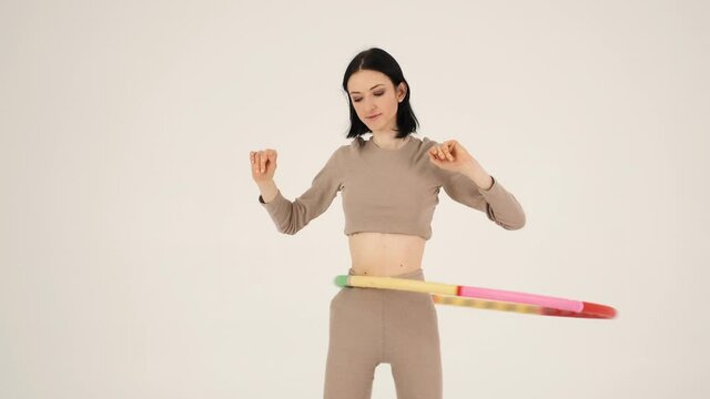 Young fit woman twisting hula hoop isolated