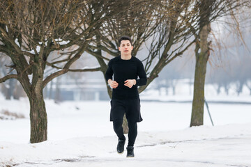 The young man goes jogging in winter while doing sports.