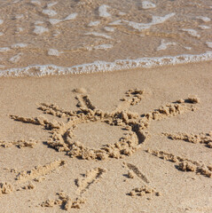 Shape of sun with incoming sea wave on sand at beach. Summer and vacation time