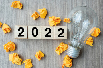 2022 text wood cube blocks and crumbled paper with lightbulb on wooden table background. New Year New Ideas, Creative, Innovation, Imagination, inspiration, Resolution, Strategy and goal concept